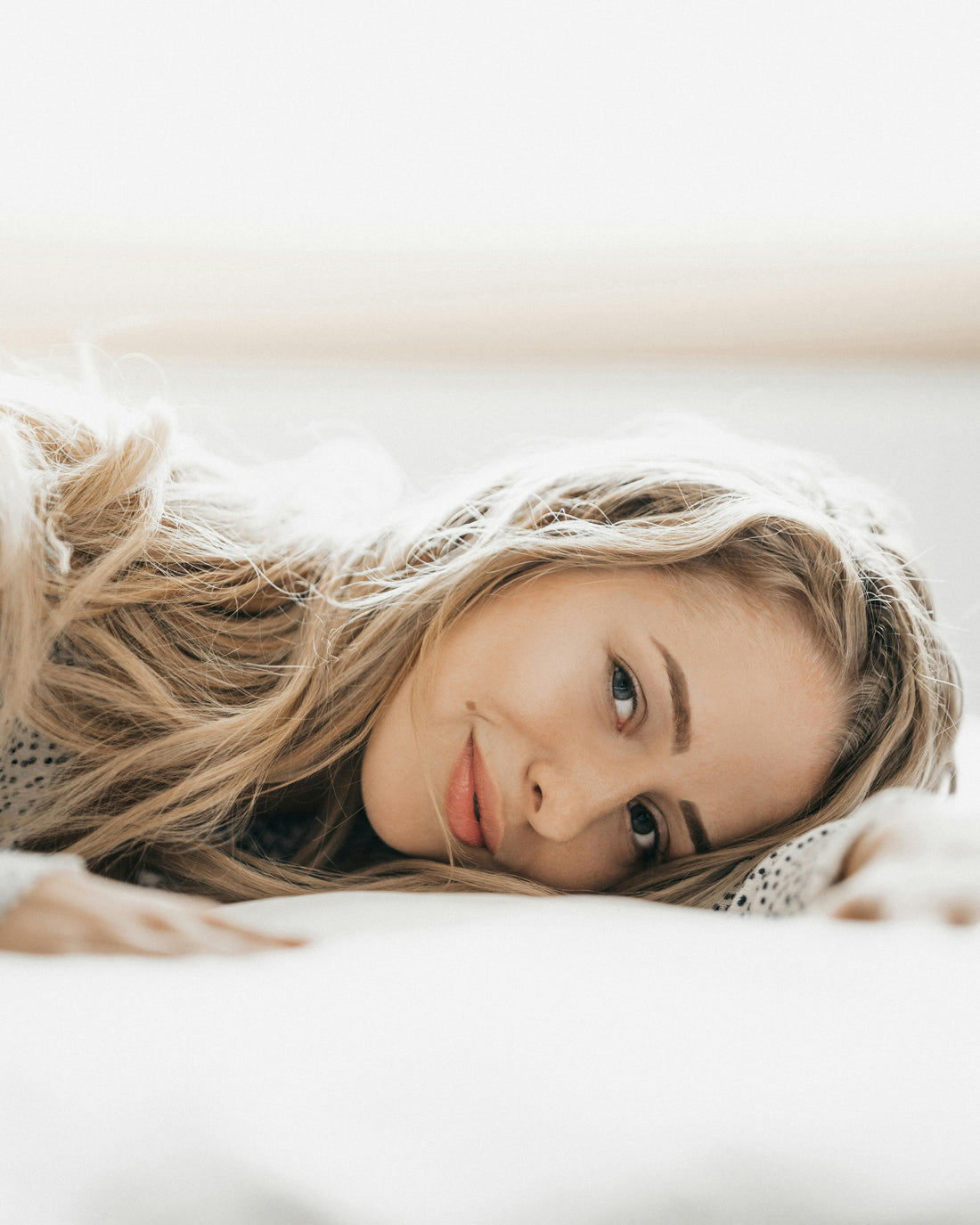 Anti-aging sleep secrets — woman waking up with smooth glowing skin after sleeping in a silk sleep mask to prevent wrinkles and sleep lines
