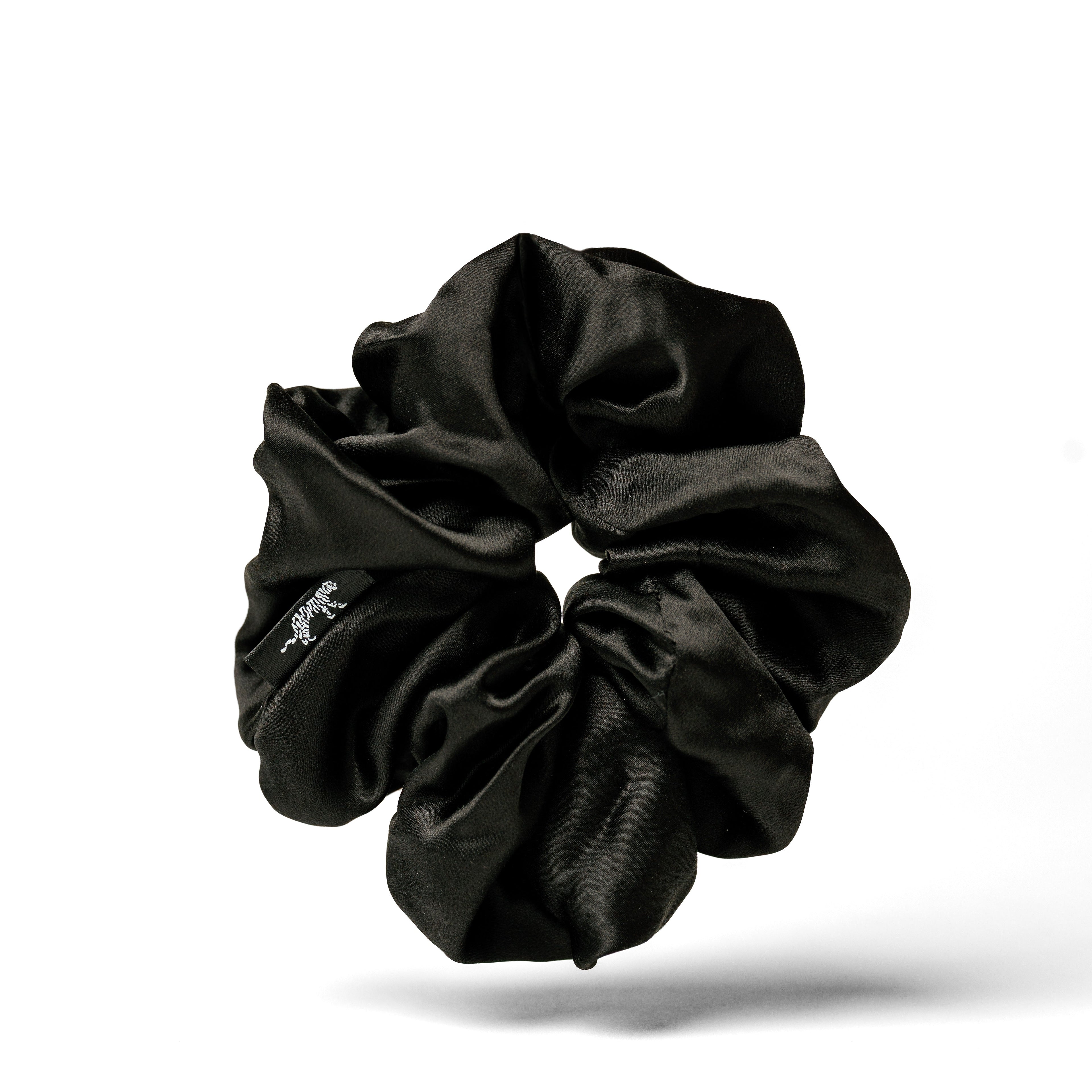 Oversized black silk scrunchie by Soreia made from organic silk, shown in close-up with soft fabric details and gentle folds.