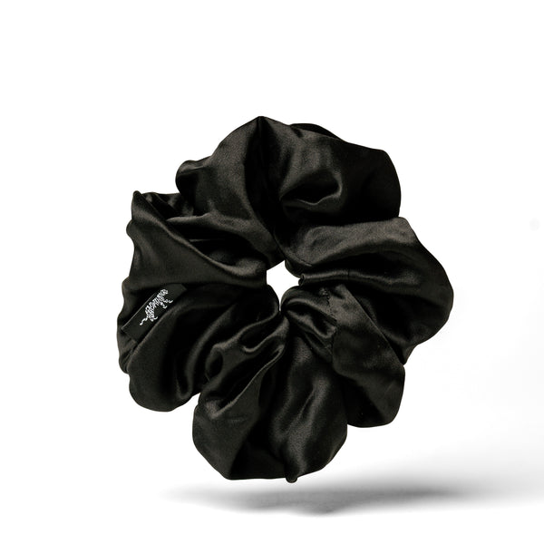 Oversized black silk scrunchie by Soreia made from organic silk, shown in close-up with soft fabric details and gentle folds.