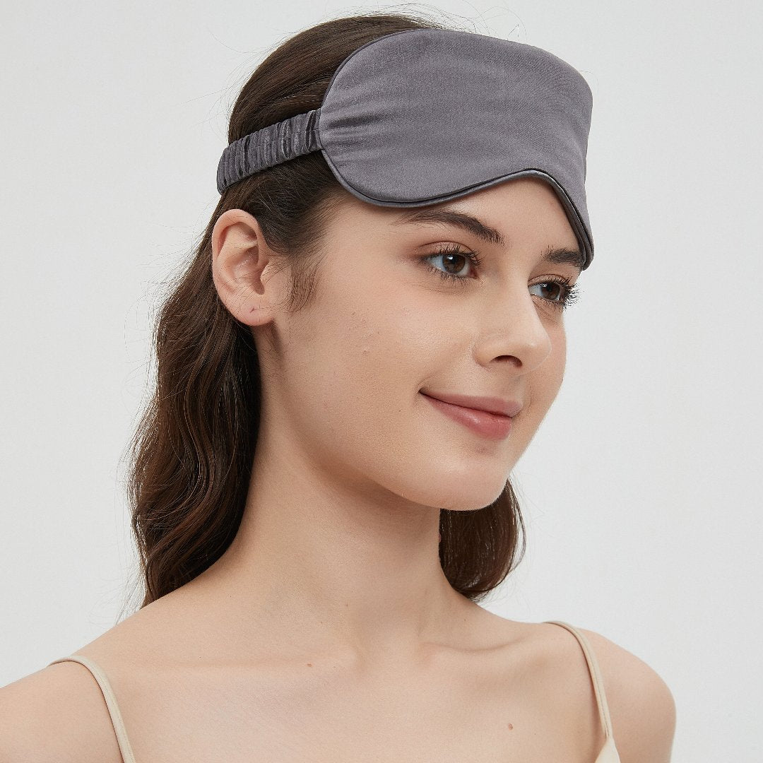 Grey Perle Silk Charmeuse Silk Sleep Mask resting gently over a pillow, showcasing soft, luxurious silk for restful sleep.