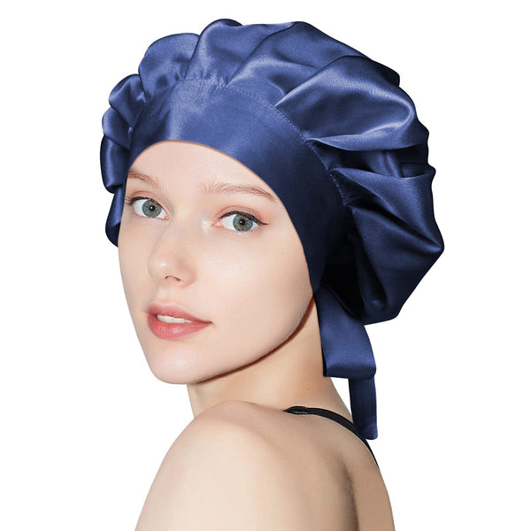 Person wearing a navy gathered sleep bonnet with a wide front band and ties at the back.