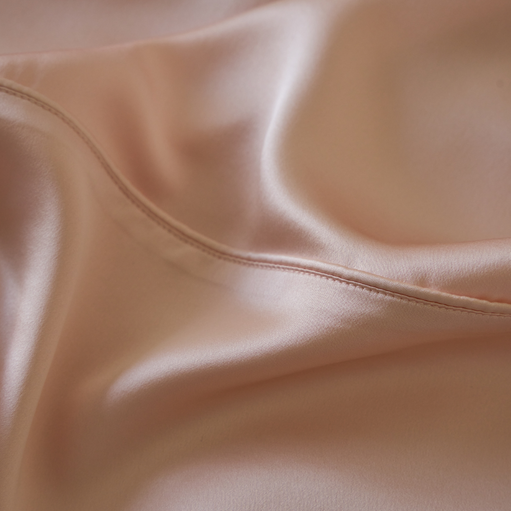 Close-up of Soreia Charmeuse silk flat sheet in Rosewood, featuring piping detail, made from pure mulberry silk, machine washable.